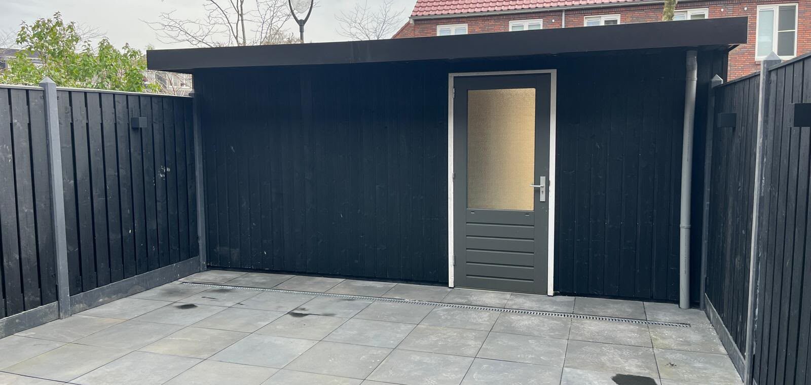 Zwarte berging met een zwarte hout-betonschutting in Ede.