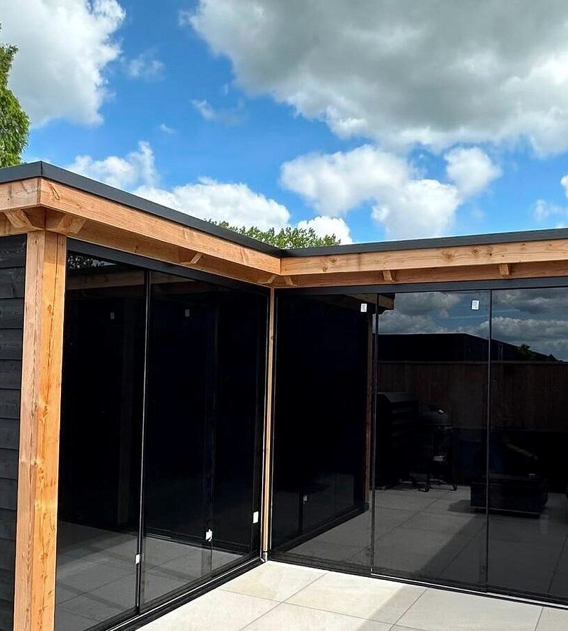 Tuinkamer in Nijkerk in L-vorm, zwart afgewerkt, met glazen schuifwanden tussen douglas stijlen.