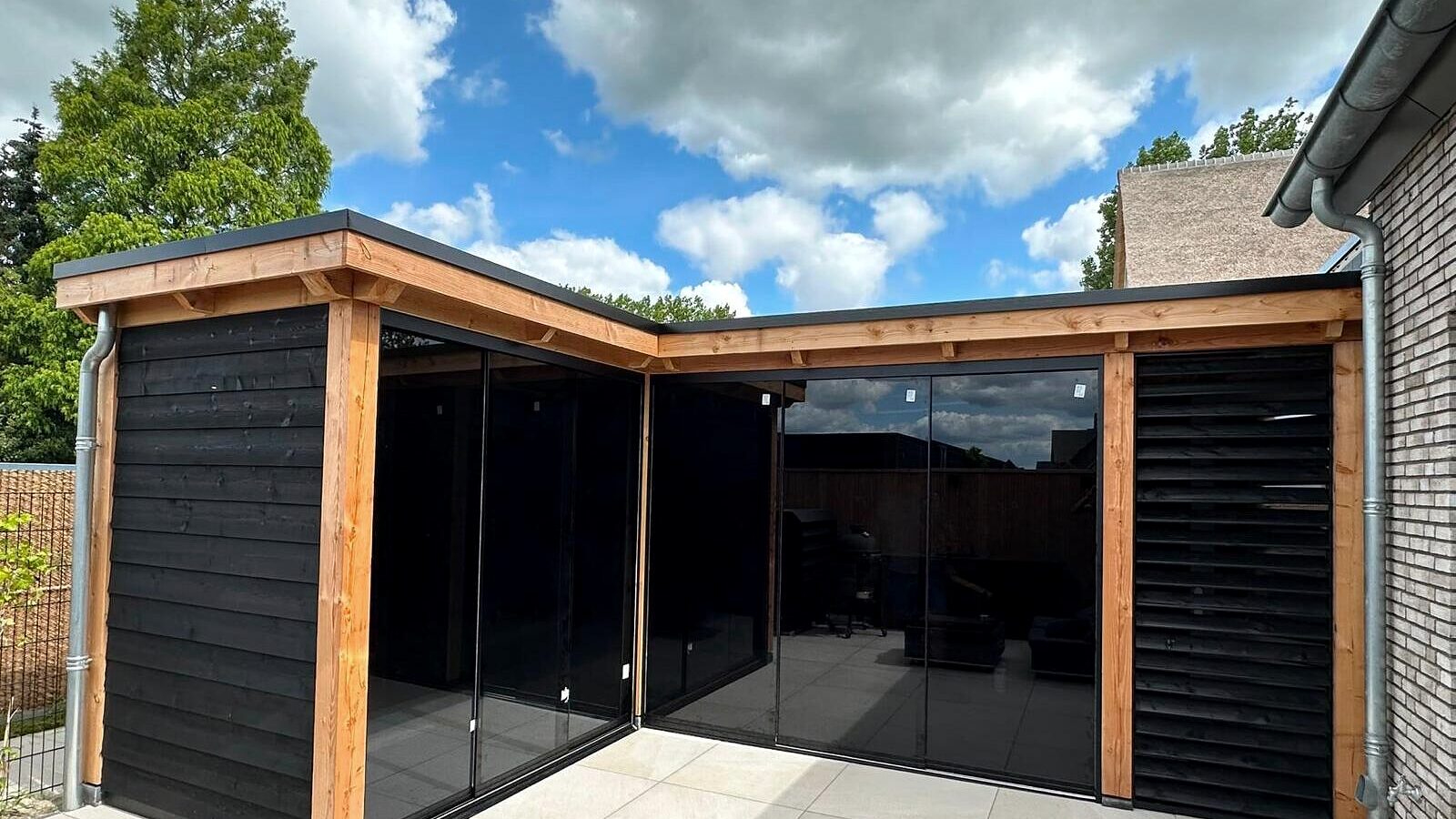 L-vormige tuinkamer in Nijkerk met een douglas constructie en getinte glazen schuifwanden.
