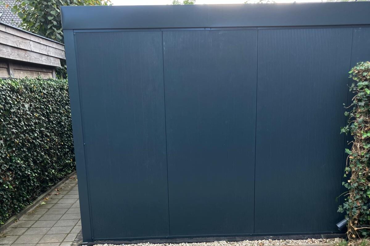 Gevel van antraciet sandwichpanelen met een strakke dakrand.