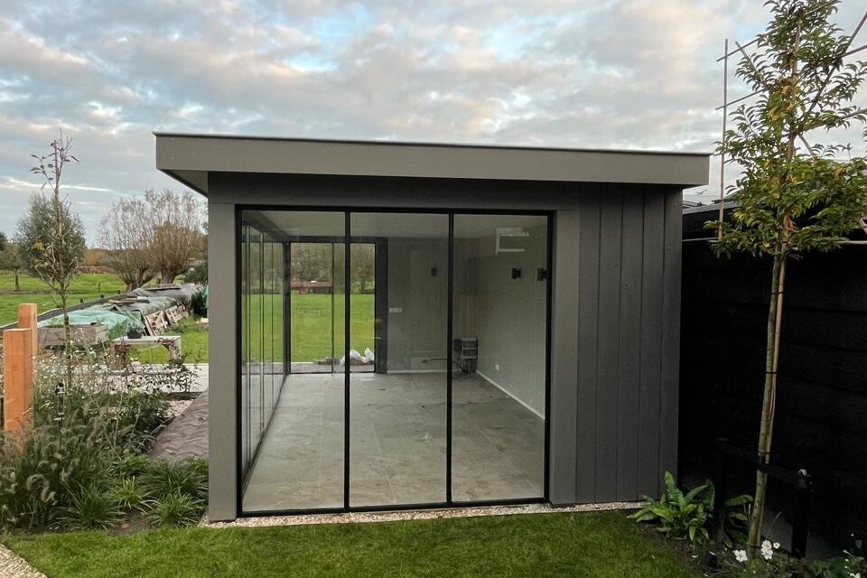 Veranda in Langbroek met glazen schuifwanden en een grijze gevel.