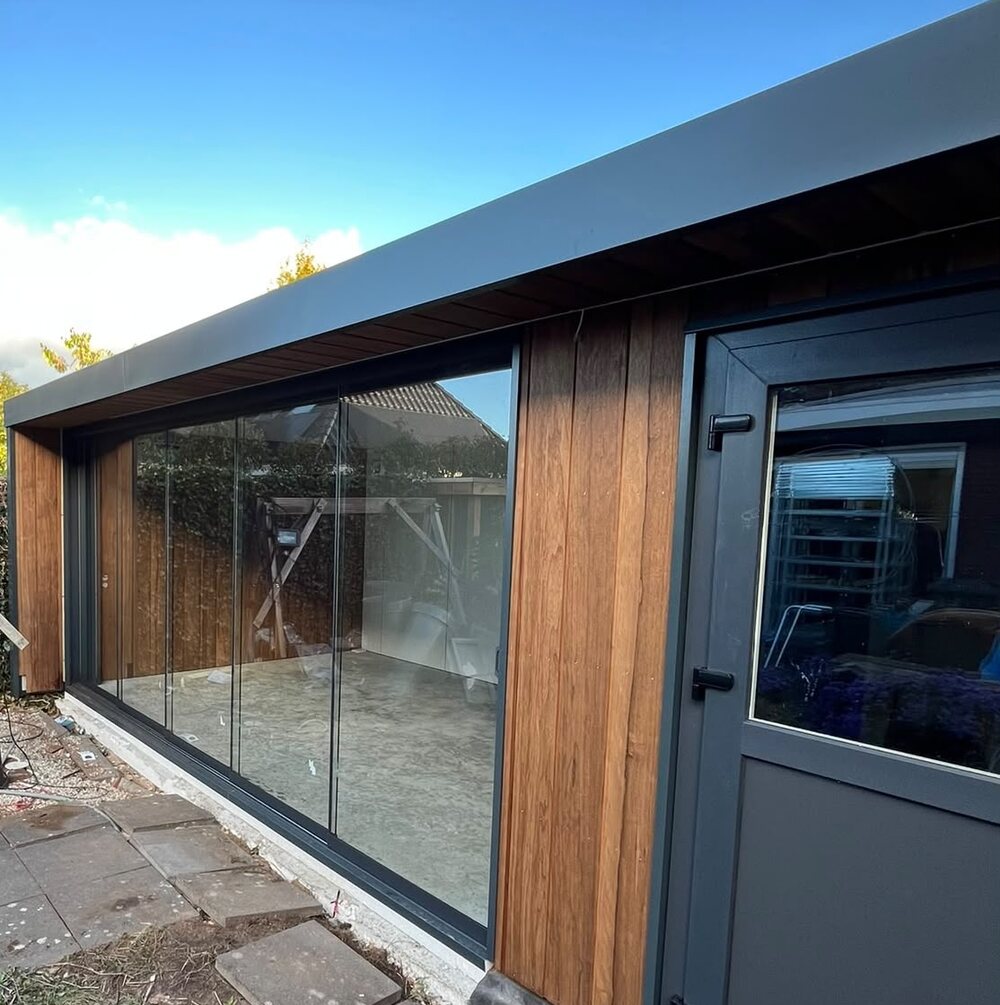 Veranda met berging in Zutphen: glazen schuifwand, gevelbekleding van thermo frake en een antraciet deur.