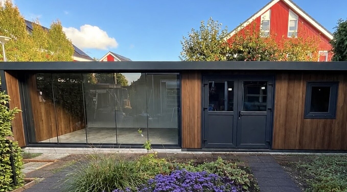 Veranda met berging in Zutphen met een glazen schuifwand, houten gevelbekleding en antraciet deuren.